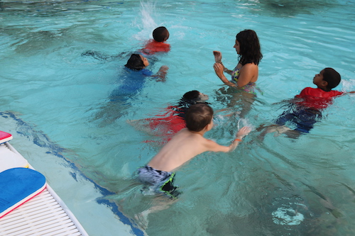 group of kids in pool learning to swim