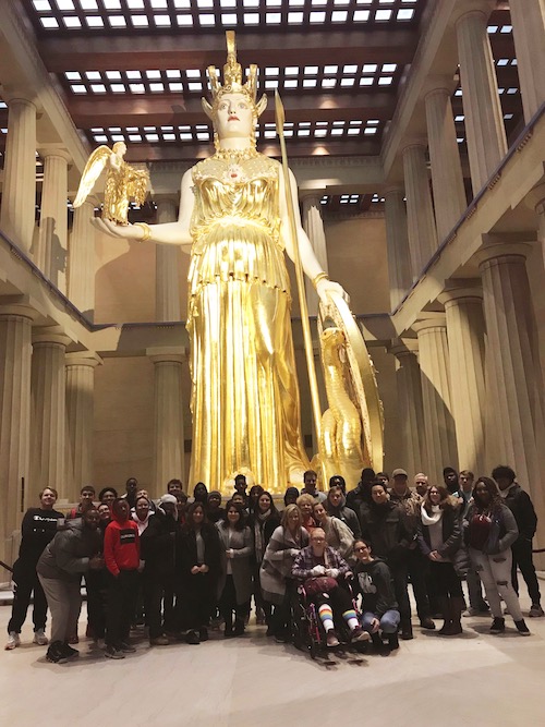 group shot in front of a big statue