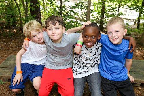 4 boys sitting on a bench in the woods