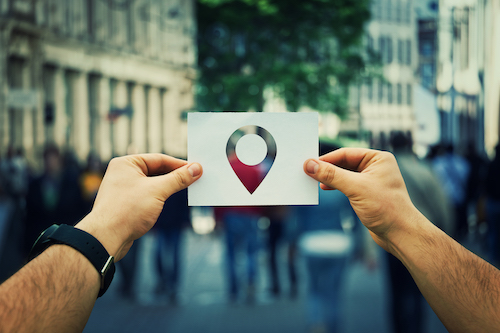 man holding google pin point above crowd