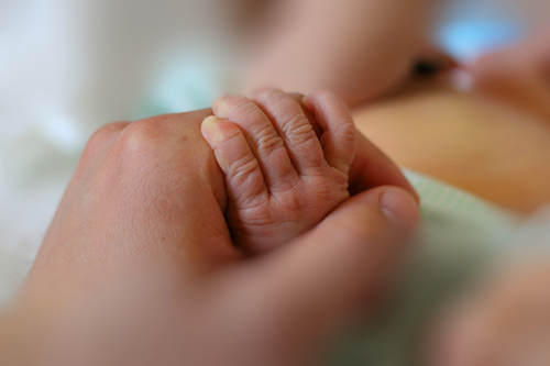 baby holding mother's hand